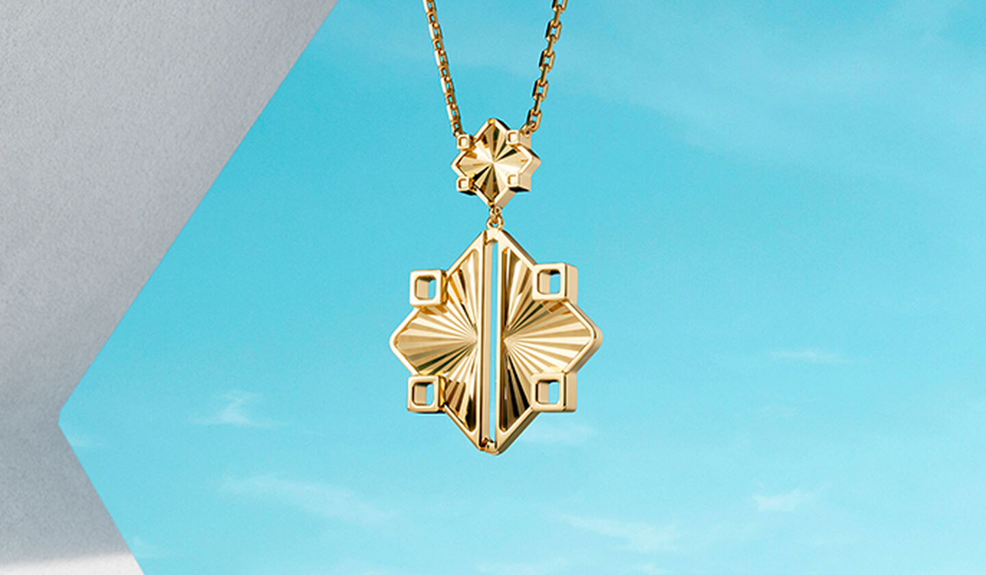 Birks Muse gold drop necklace on a blue background.